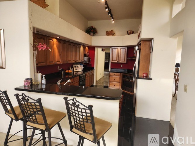 A kitchen with brown chairs and a black counter.