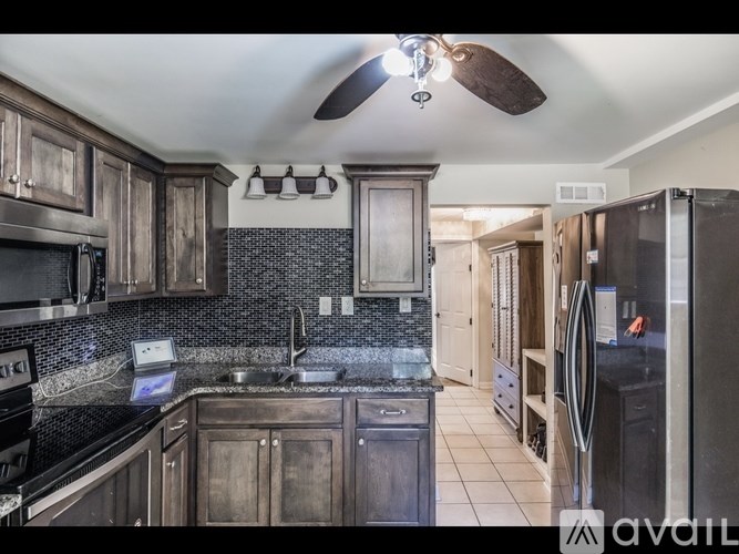 A kitchen with dark wood cabinets and a black fridge.