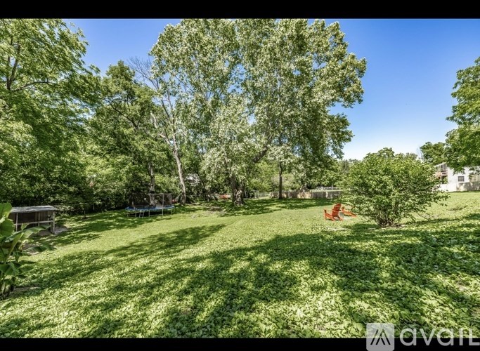 A sunny day in a lush green backyard with a picnic table and a swing set.