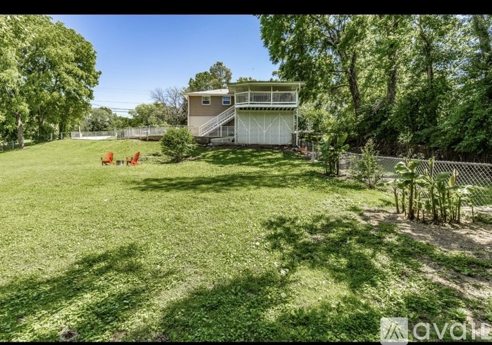 A house with a green lawn and trees in the background.