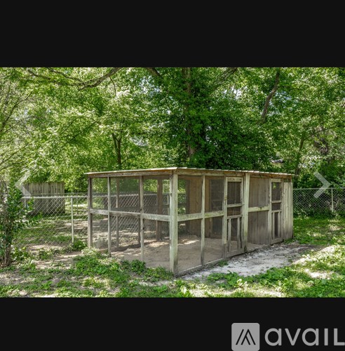 A wooden structure surrounded by a fence in a green area.