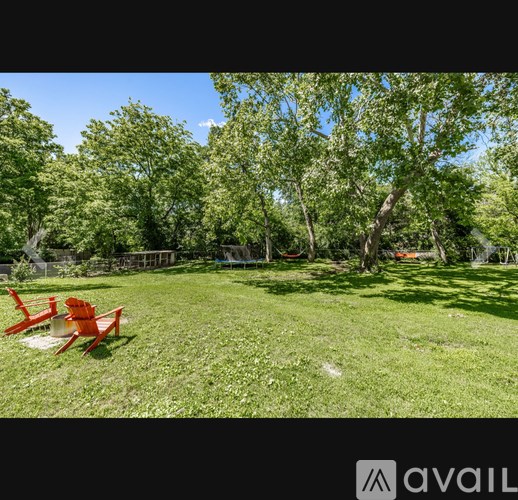 A backyard with a red chair and a white container on the grass.