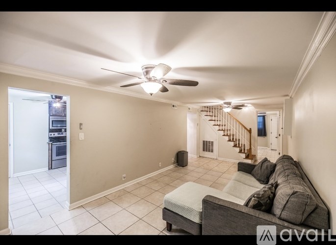 A living room with a grey couch and a fan on the ceiling.