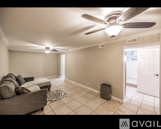 A living room with a couch, a fan, and a rug.