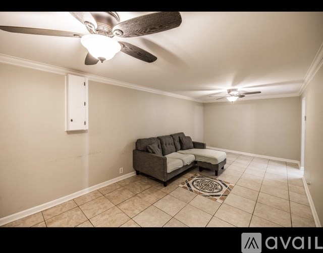 A living room with a grey couch and a ceiling fan.
