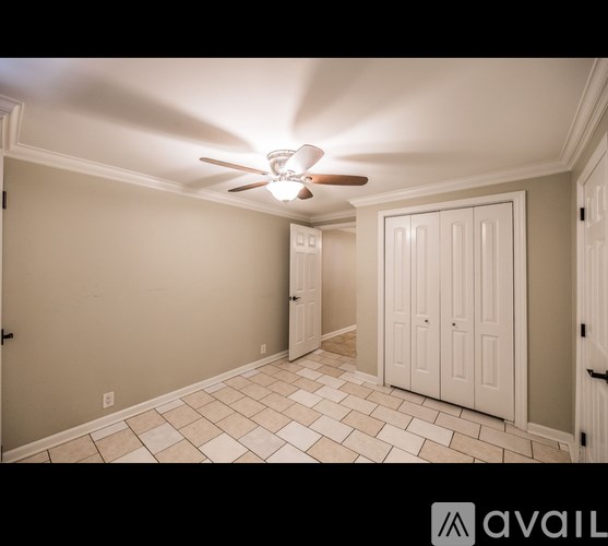A room with a ceiling fan and tile flooring.