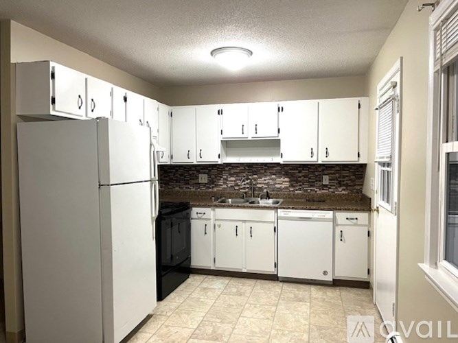 A kitchen with white cabinets and a black dishwasher.