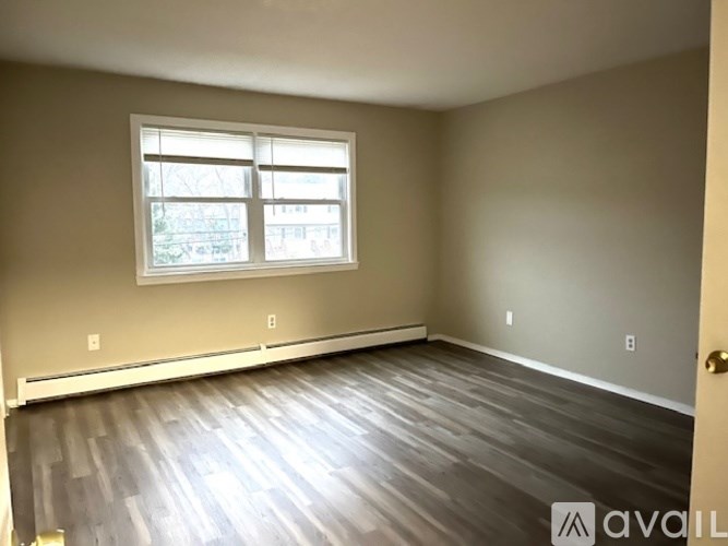 A room with a window and wooden flooring.