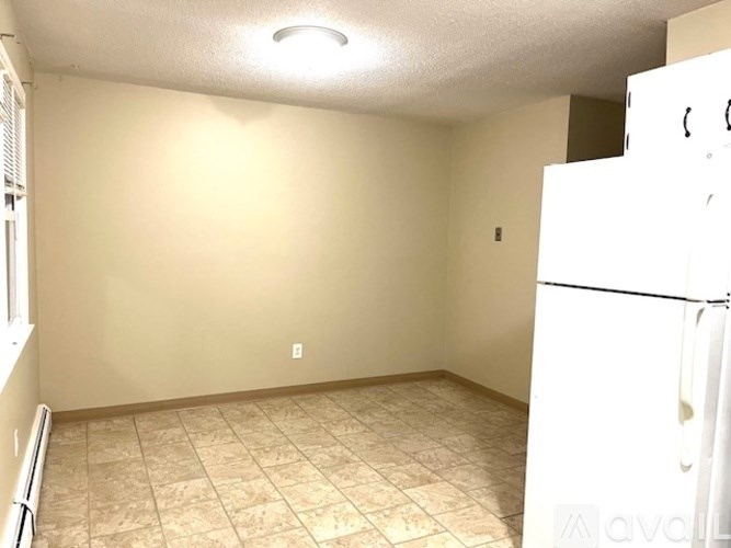 A room with beige walls and a white refrigerator.