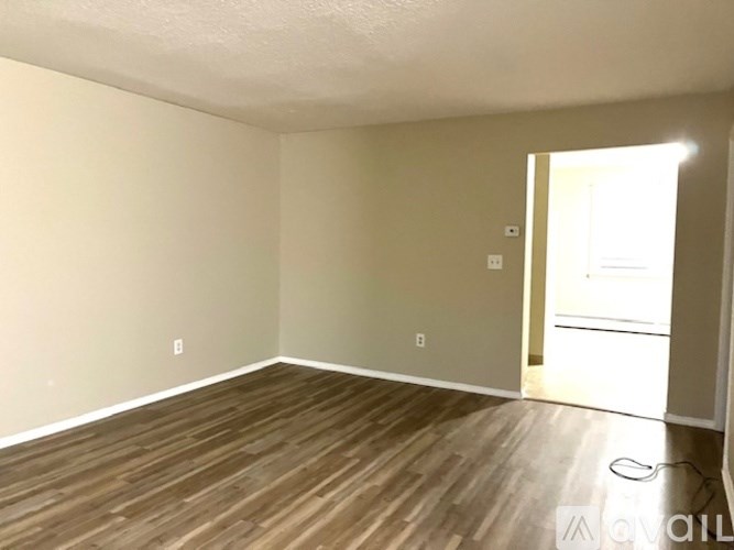 A room with wooden flooring and a doorway leading to another room.