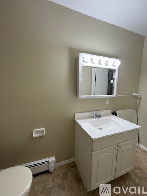 A bathroom with a toilet, sink, and mirror.
