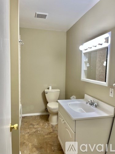 A bathroom with a toilet, sink, and mirror.