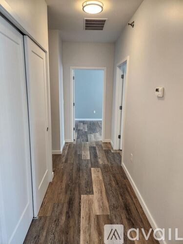 A hallway with wood flooring and white walls.