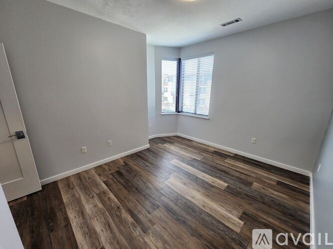 A room with wooden flooring and a window with blinds.