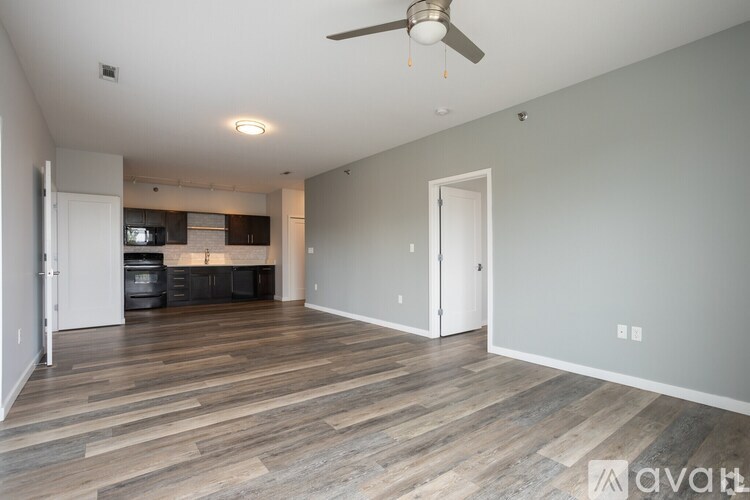 A spacious room with wooden flooring and a ceiling fan.