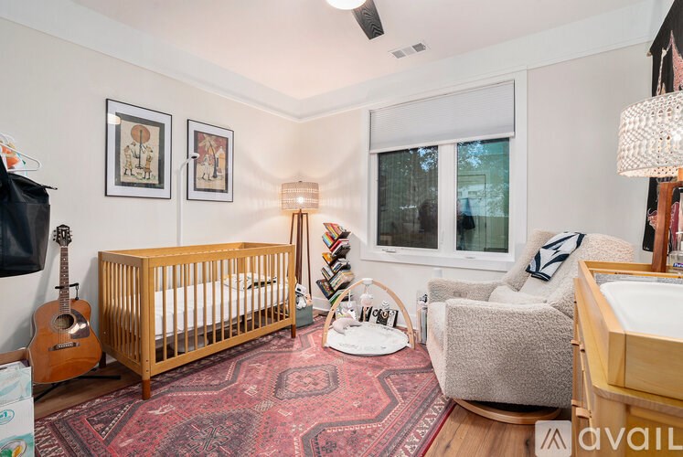 A baby's room with a crib, chair, and guitar.