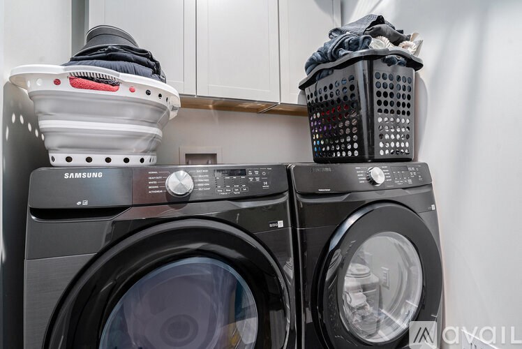 A Samsung washing machine with a basket of clothes on top of it.