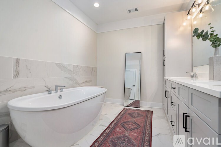 A bathroom with a white tub and a red rug.