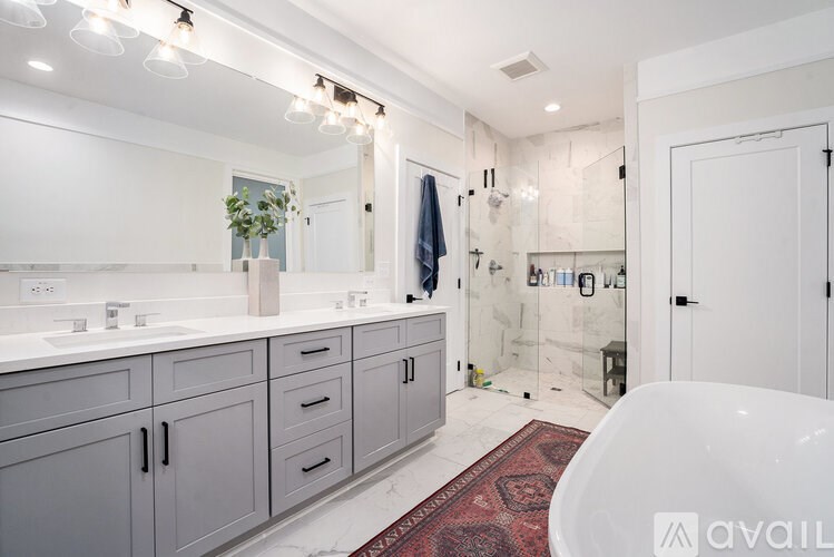 A bathroom with a white tub and grey cabinets.