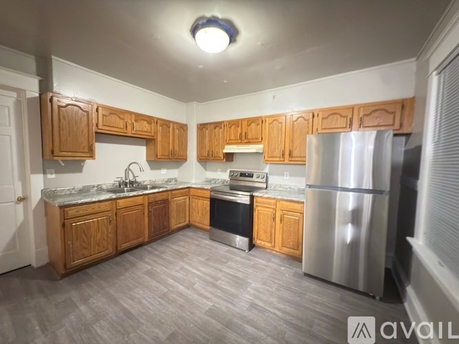 A kitchen with wooden cabinets and a stainless steel refrigerator.