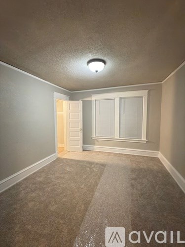 A room with a carpeted floor and a window with a white frame.