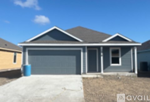 A house with a grey roof and a blue barrel in front.