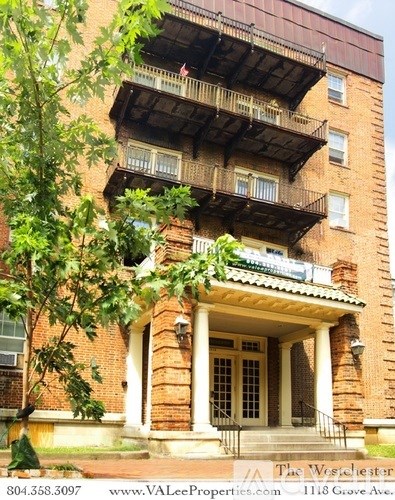 A red brick building with a balcony and a porch.