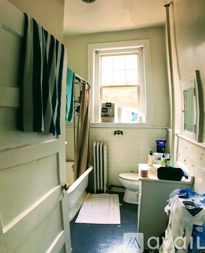 A bathroom with a toilet, sink, and a window.