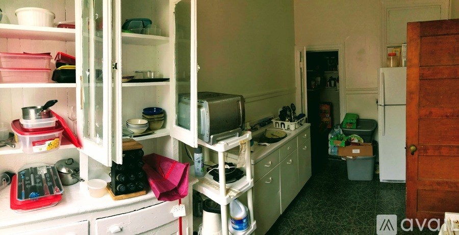 A kitchen with white cabinets and a red bag on the counter.