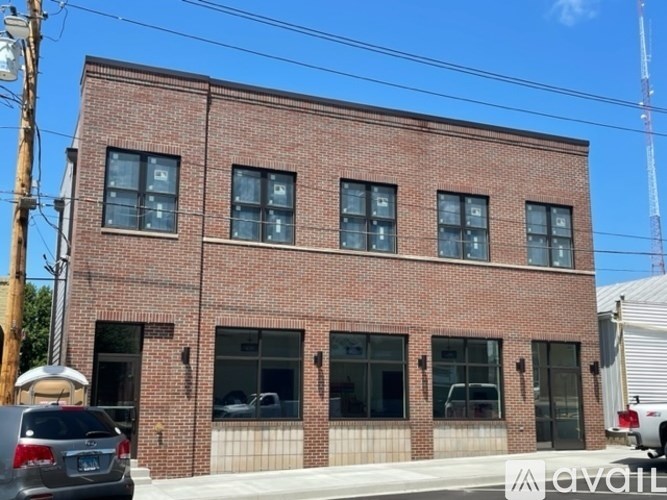 A red brick building with a white car parked in front.
