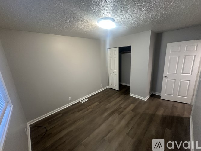 A room with wooden flooring and two doors, one of which is open.