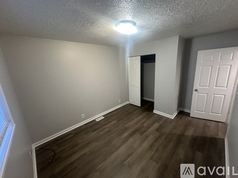 A room with wooden flooring and two doors, one of which is open.