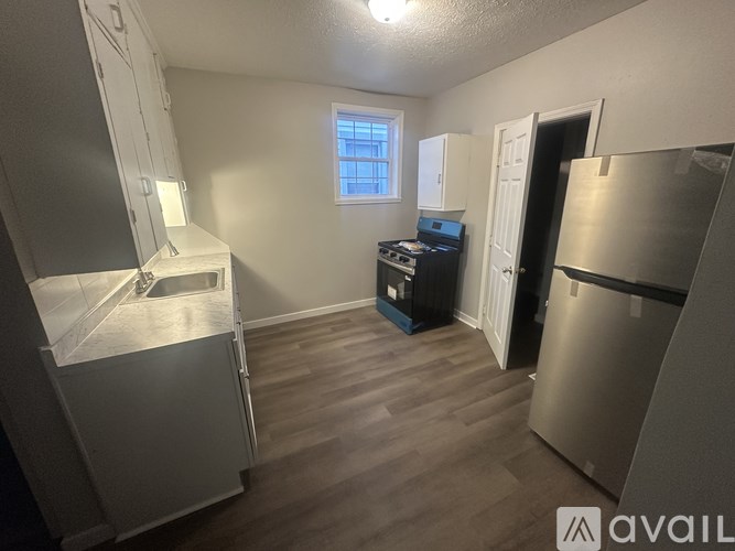 A kitchen area with a stove, refrigerator, and a window.