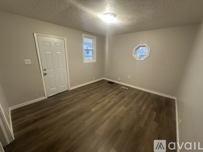 A room with wooden flooring and a round window.