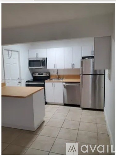 A kitchen with white cabinets and a wooden counter.