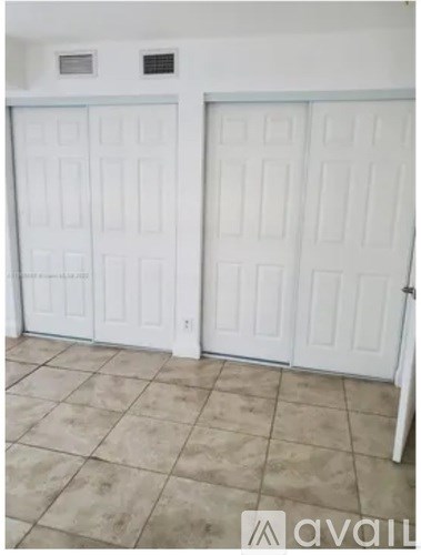Two white doors in a room with tiled flooring.
