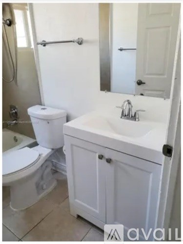 A white bathroom with a toilet, sink, and mirror.