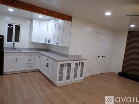 A kitchen with white cabinets and a wooden floor.
