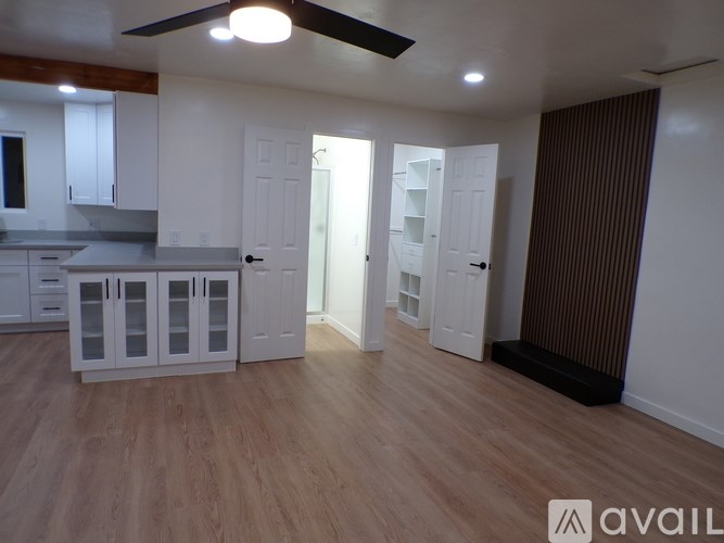 A room with a kitchen area and a living area with a ceiling fan.
