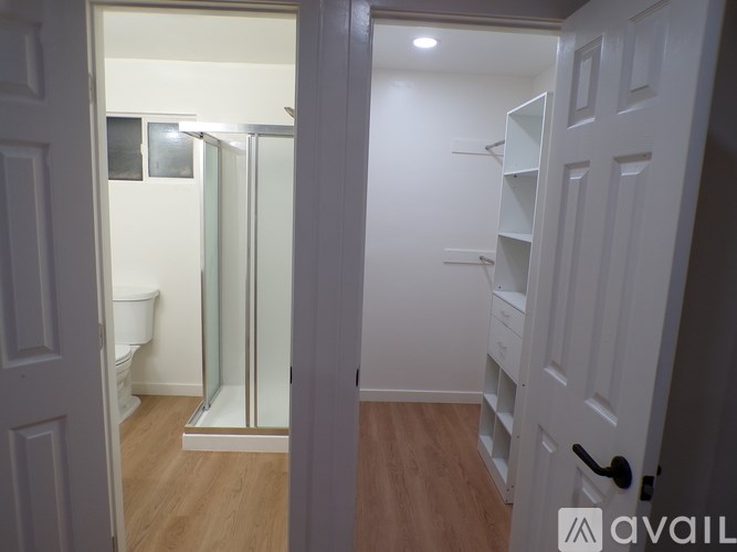 A white door is open to a bathroom with a toilet and a walk-in shower.