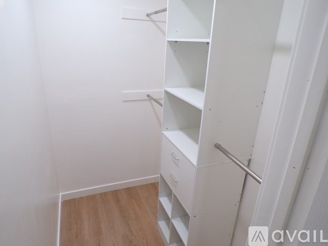 A white shelving unit in a room with wooden flooring.