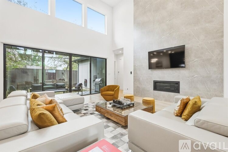 A modern living room with a white couch and a television mounted on the wall.