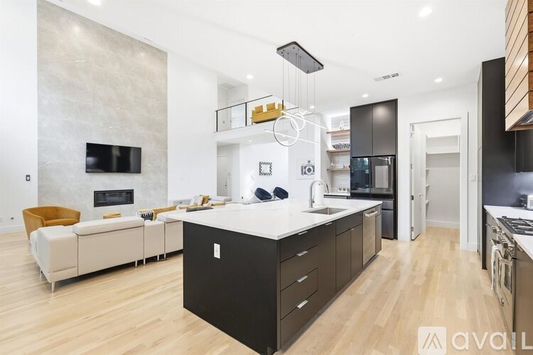 A modern kitchen with a white island and black cabinets.