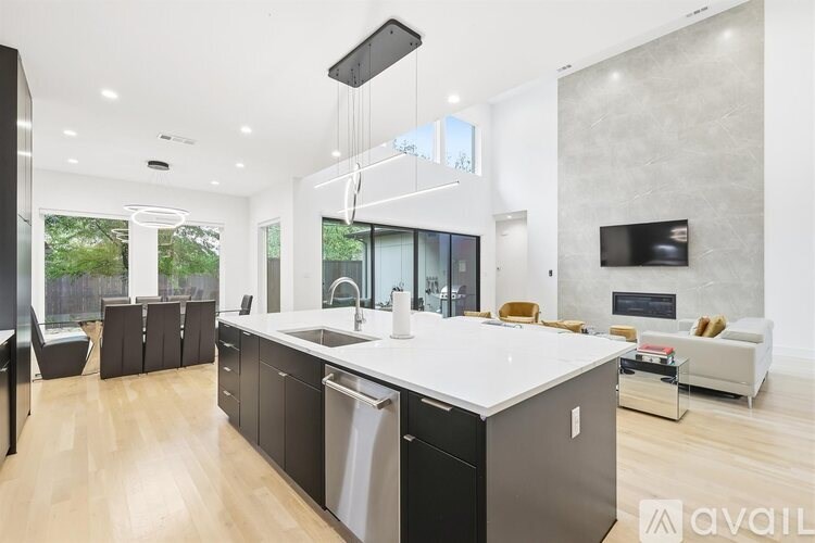 A modern kitchen with a large island and a TV mounted on the wall.