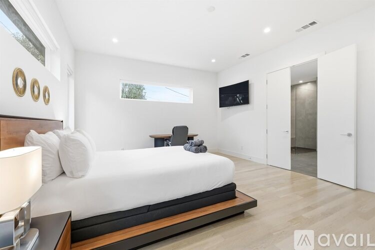 A bedroom with a large bed and a flat screen TV mounted on the wall.