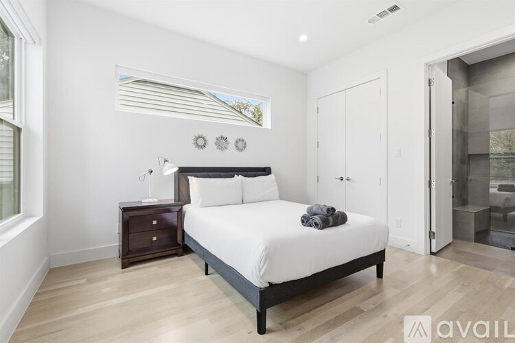 A bedroom with a bed, nightstand, and a window with blinds.