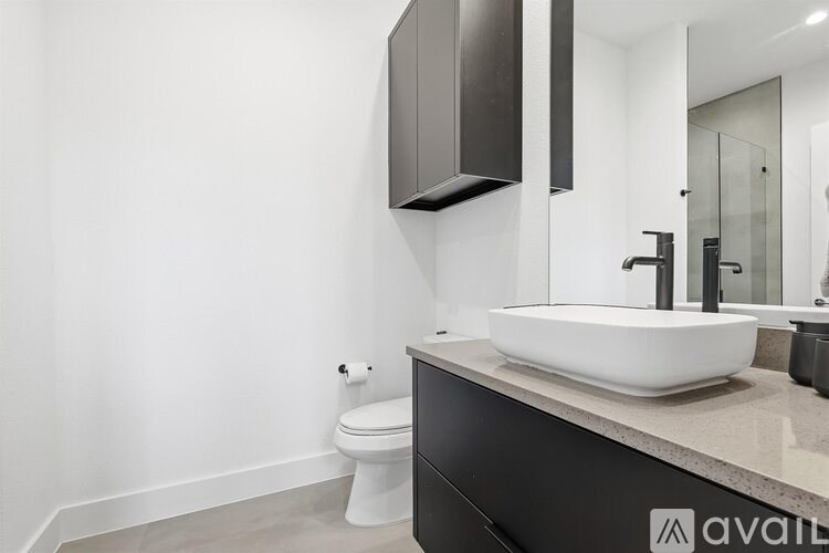 A modern bathroom with a white sink and black cabinetry.