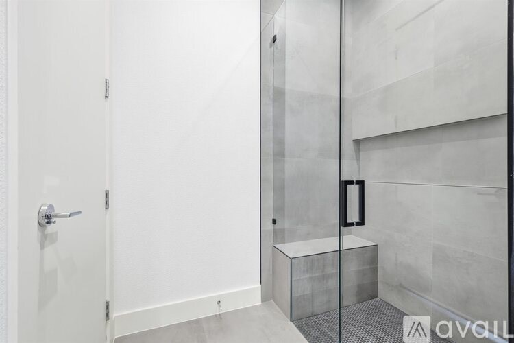 A bathroom with a glass shower door and a white door.