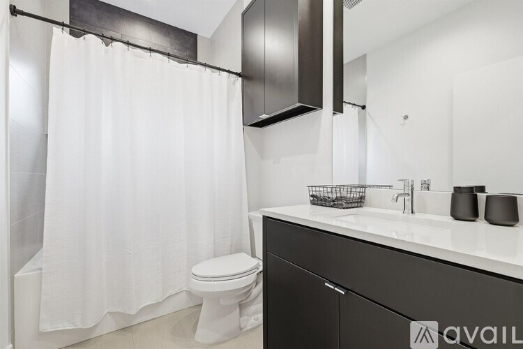 A white toilet sits next to a white shower curtain in a bathroom.
