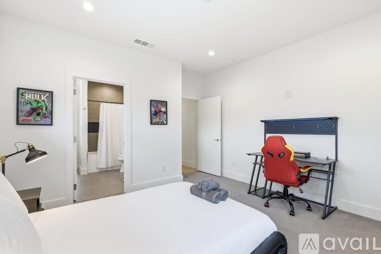 A bedroom with a bed, desk, and two posters on the wall.